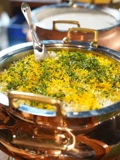 A beautiful shot of our vegetable biryani, layered with fragrant rice and herbs, ready to be served from a traditional copper pot.