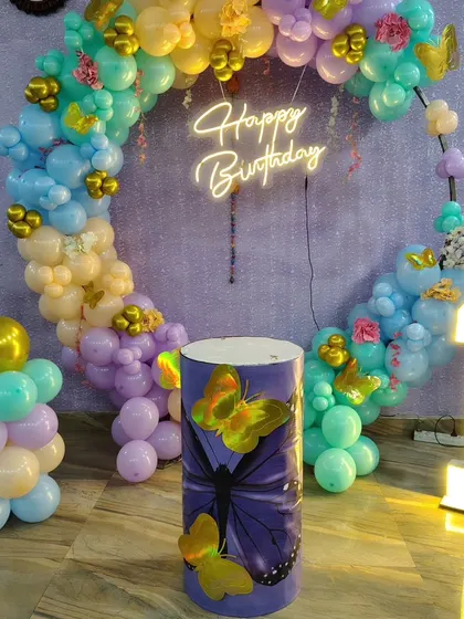 The complete setup for a first birthday with a butterfly theme, showing the circular balloon frame and custom decor elements.
