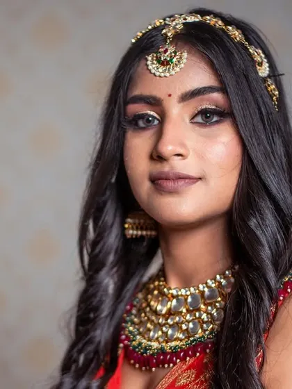 A direct and confident portrait. The makeup is bold and defined, showcasing a strong brow, winged liner, and perfectly contoured features.