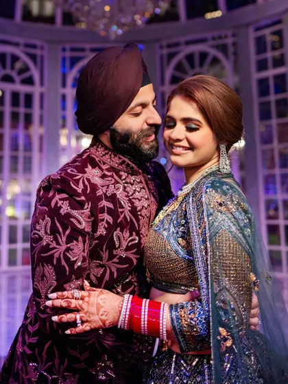 Sahib and Muskan in a loving embrace, showcasing their richly detailed and colorful sangeet outfits. We pay close attention to capturing the beauty of Indian couture.