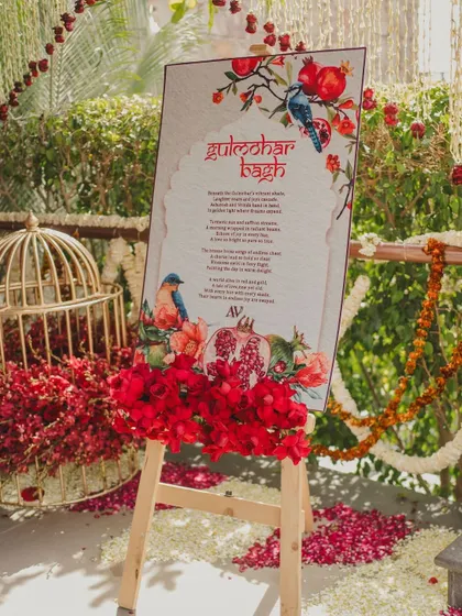 The welcome sign for the 'Gulmohar Bagh' event, adorned with fresh red flowers.