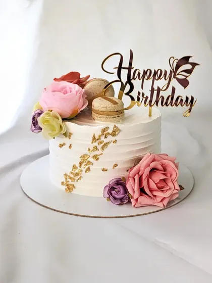 A simple floral beauty for a birthday. This textured white buttercream cake is decorated with fresh flowers, macarons, and a touch of gold leaf.