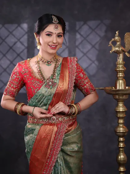 This bride looks so serene and beautiful. She is wearing a traditional kemp jewellery set with a choker and haram that perfectly matches her green and red silk saree.