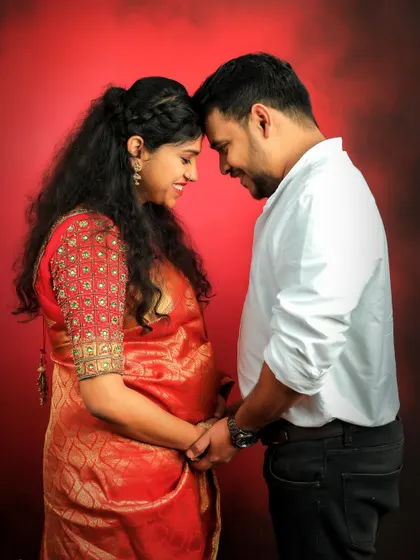 A tender moment between an expecting couple. This studio portrait uses a rich red backdrop to create a feeling of warmth and intimacy for their traditional shoot.