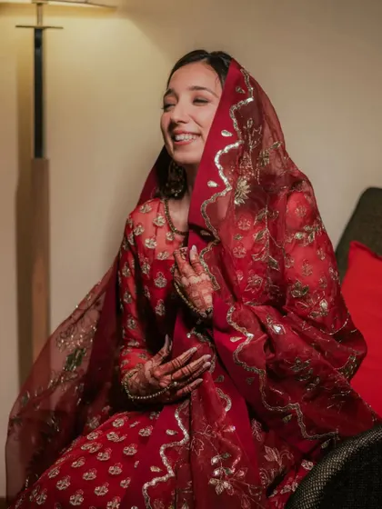The bride's smile says it all. Her soft glam makeup enhances her natural beauty, and the red dupatta adds a touch of traditional elegance.