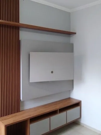 This TV unit features a combination of wood-fluted paneling and a simple grey back panel. The design includes an open shelf and a low console with drawers, offering both display space and concealed storage.