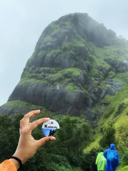 A creative shot holding our Kurinjal trek badge up to the actual peak. It's a great way to capture the memory of your climb.