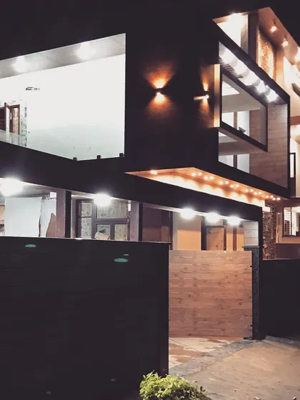 A night view of the industrialist's bungalow during the final stages of construction. The exterior lighting strategy was designed to accentuate the building's geometric forms and create a dramatic, layered effect.