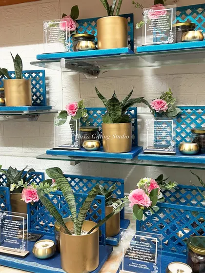 A display of the "Green Card Journey" gratitude hampers, showing the elegant combination of the blue jaali platter, golden planter, and personalized acrylic card.