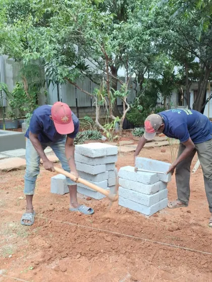 Teamwork in action. Two of my crew members are seen preparing the ground and stacking pavers, getting ready to build a new pathway or patio.