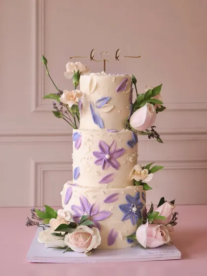 For the big days, we love creating something truly special. This three-tiered wedding cake features delicate, hand-painted watercolor flowers in shades of lavender and is adorned with fresh roses, making it a beautiful centerpiece for a memorable celebration.
