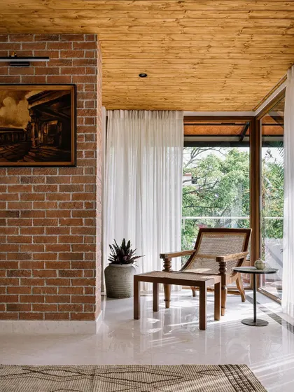 This space combines an exposed brick wall with a warm pine wood ceiling. The mix of textures creates a rustic yet modern feel, perfect for a relaxed living area.