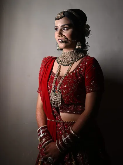 A dramatic and artistic shot of our bride. The lighting accentuates the rich color of her lehenga and the sharp, clean lines of her makeup.