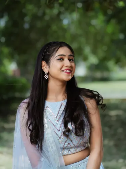 A beautiful outdoor portrait in a light blue lehenga. The natural light and green background create a fresh and airy feel.