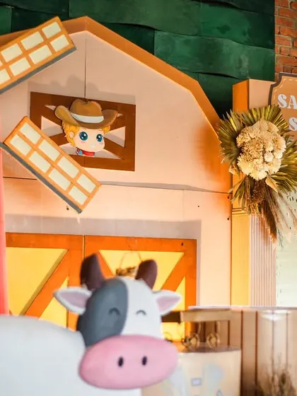 A detailed shot of the barn backdrop, featuring a friendly cow and a spinning windmill. The warm lighting from within the barn adds a cozy and inviting glow.