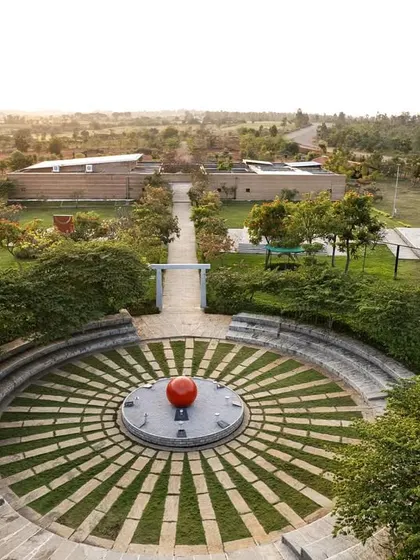 An aerial view of the stone amphitheater at the H.N. Science Center, a space designed for community gathering and learning. The design integrates with the landscape, using local stone and grass to create a functional yet organic public space.