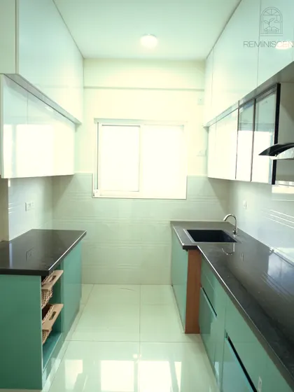 This perspective shows the clean, galley-style layout of the green and white kitchen. The design includes open wicker basket storage, adding a natural, rustic element to the modern space.