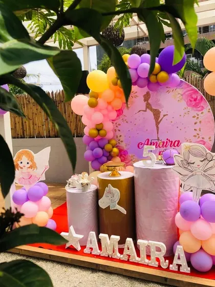 A beautiful outdoor setup for a ballerina and fairy party. The decor features a custom circular backdrop, marquee letters, and character props that look wonderful in natural light.