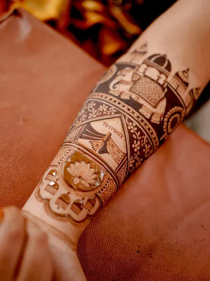A close-up of the forearm, showing the intricate details of the elephant and dhol motifs. The negative space technique makes the figures stand out beautifully.