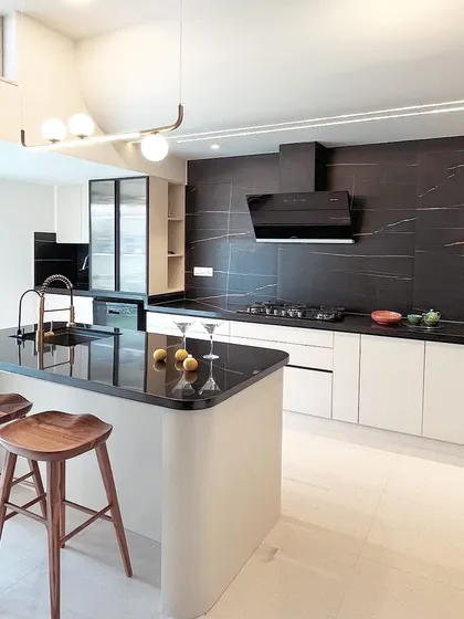 In this dual-toned kitchen, I used stark black tiles to create a dramatic contrast with the taupe cabinets. The large island with wooden bar stools serves as the central hub for the space.