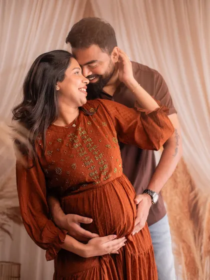 A joyful and candid embrace. The boho-chic props like pampas grass add a stylish and modern touch to the studio session.