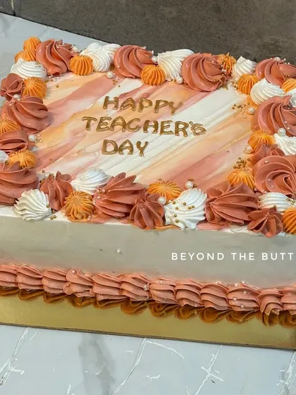 A beautiful rectangular cake for Teacher's Day with piped details in shades of orange.