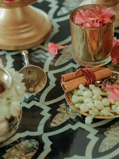 A beautiful arrangement of jasmine, pink flowers, and cinnamon sticks on a brass plate. The combination of fragrant flowers and spices engages all the senses.