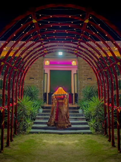 A creative shot of the bride walking through a lit archway, creating a mysterious and grand entrance photo.