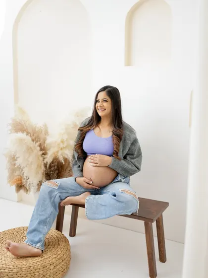 A relaxed and happy portrait in a modern boho setting. The mom-to-be's casual outfit and joyful expression create a fresh and authentic look.