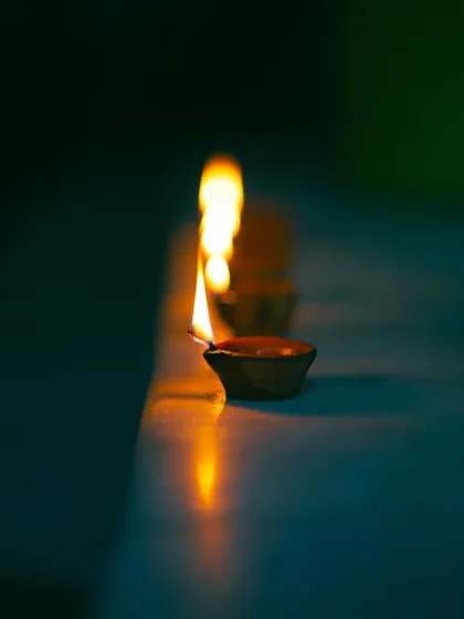 A line of diyas glowing on a ledge. The repetition and the soft bokeh effect create a simple yet mesmerizing image that embodies the spirit of Diwali.