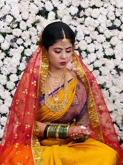 The bride during a wedding ritual, her face framed by a vibrant red veil. The makeup stands out beautifully.