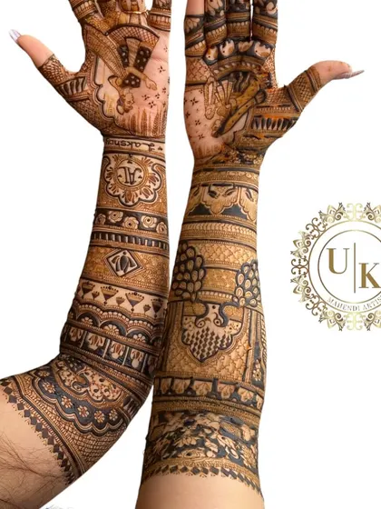 A unique angle showing the full length of this intricate bridal mehandi. The design features portraits and traditional patterns that wrap all the way around the arms.