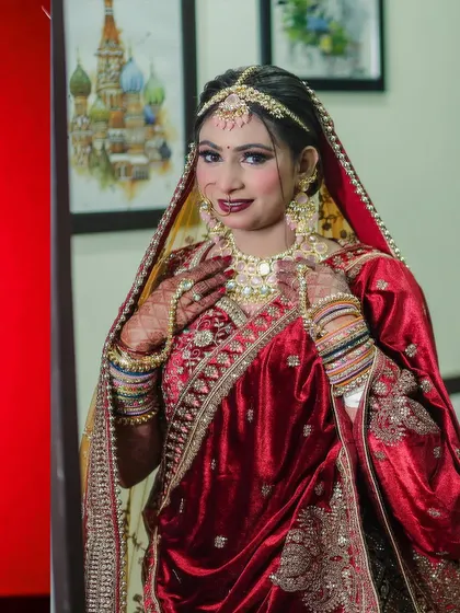 A classic bridal portrait where the bride looks directly at the camera. Her hands frame her necklace, drawing attention to the intricate jewelry and her confident expression.