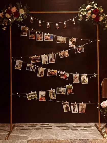 A wonderful way to display cherished memories. This custom photo stand with fairy lights and floral accents is a perfect, heartfelt addition to an anniversary or milestone birthday party.
