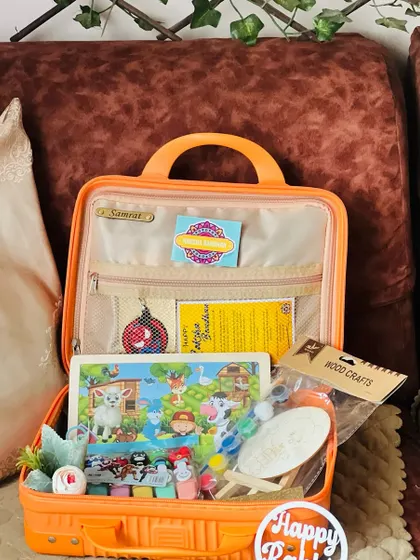 An activity-filled Rakhi hamper for a child, packed in a mini suitcase. It includes a puzzle, wood crafts, and other engaging toys.