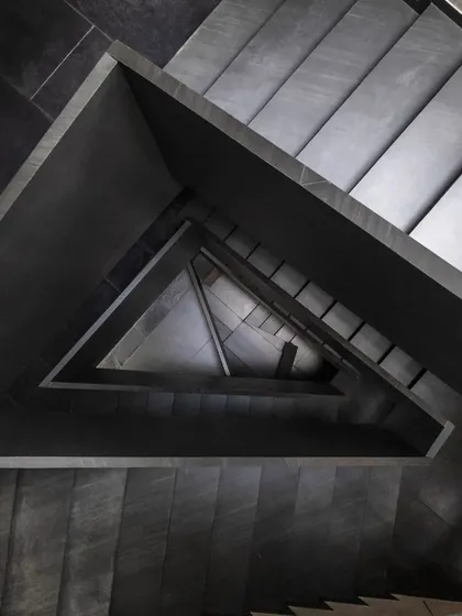 A detail from the Brick House, where the staircase is treated as a sculptural element. The interplay of black pigmented lime plaster, raw concrete, and natural light creates a dramatic, Escher-like geometry that evolves as you move through the space.