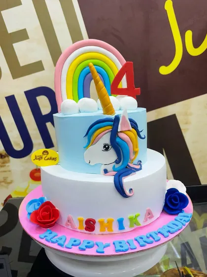 A 3kg two-tiered unicorn cake with a rainbow topper, perfect for a 4th birthday celebration.
