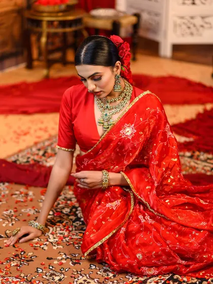 A graceful pose on a traditional carpet, surrounded by red fabric. This shot creates a rich and luxurious scene, full of color and texture.