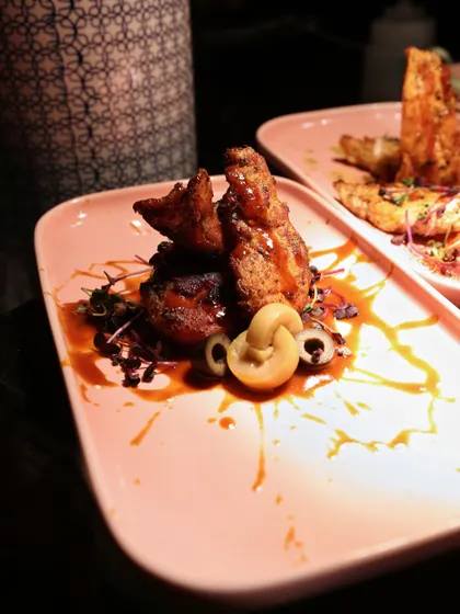 A tower of crispy, saucy chicken from our "Flames of the Orient" menu. The height and texture of the dish create a dramatic presentation, complemented by a rich, glossy sauce.