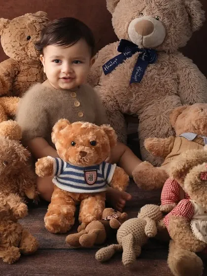 The king of the teddies. This portrait captures a sweet, interactive moment between the baby and his teddy bear friends. The warm brown tones make it feel extra cozy.