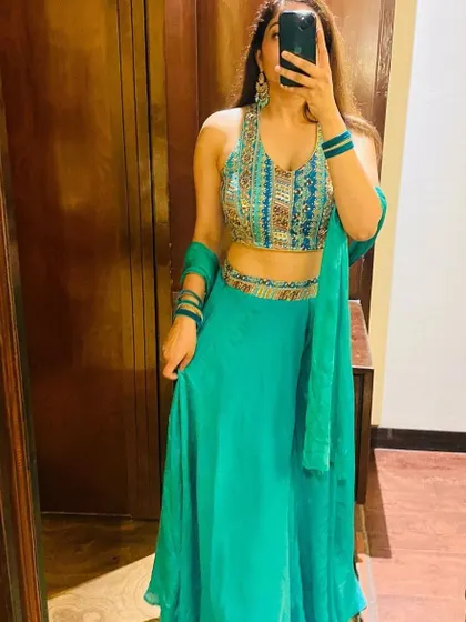A mirror selfie showing off a lovely turquoise lehenga with a colorful embroidered blouse. A great rental choice for a beach wedding or a summer function.