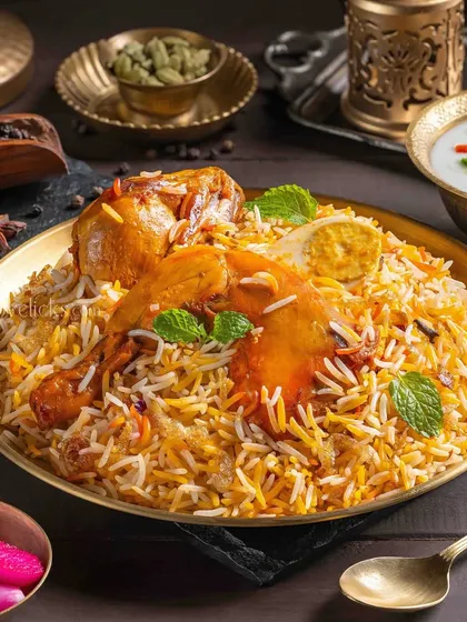 A classic Chicken Biryani with a boiled egg, garnished with mint and served in a traditional brass plate.