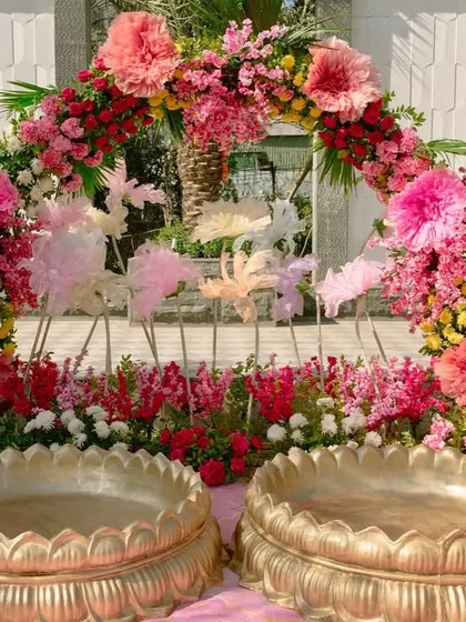 The Haldi ceremony spot, with two large brass urlis set before a beautiful arch of pink, yellow, and red flowers.