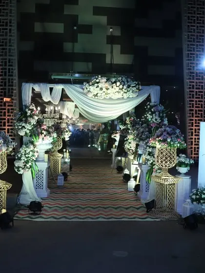 A dreamy nighttime entrance. I used soft white drapes and abundant floral arrangements, illuminated to create a magical glow against the dark, guiding guests into a sophisticated and elegant wedding reception.