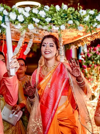 The bride, under the 'phoolon ki chadar', waves happily as she makes her way to the mandap, her face radiant.