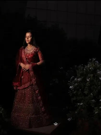 A dramatic portrait using creative lighting to highlight the bride in her red lehenga against a dark background.