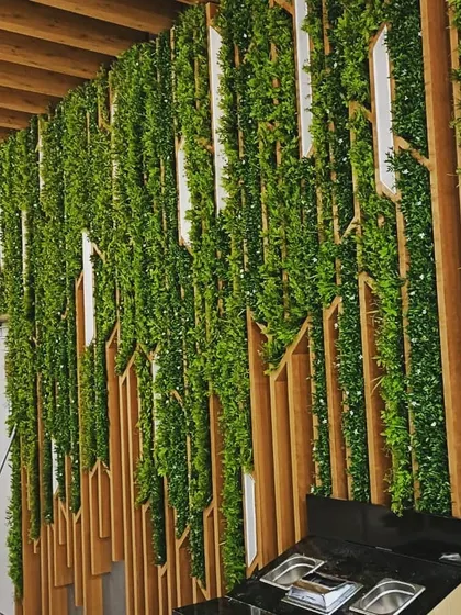 This is a unique artificial green wall I designed for a restaurant space. I integrated the greenery with custom-cut wooden panels to create a dynamic, textured look that complements the modern interior design.
