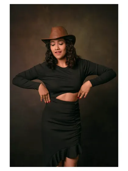 A joyful portrait of a model in a black dress and cowboy hat. Her expression is full of life and energy.