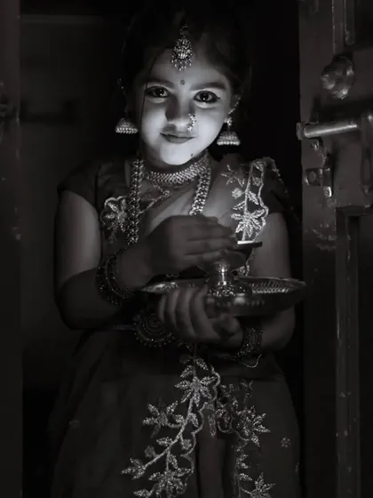 Little Saanvi looking like a traditional doll, holding a lamp. Her custom outfit was designed for a festive photoshoot.