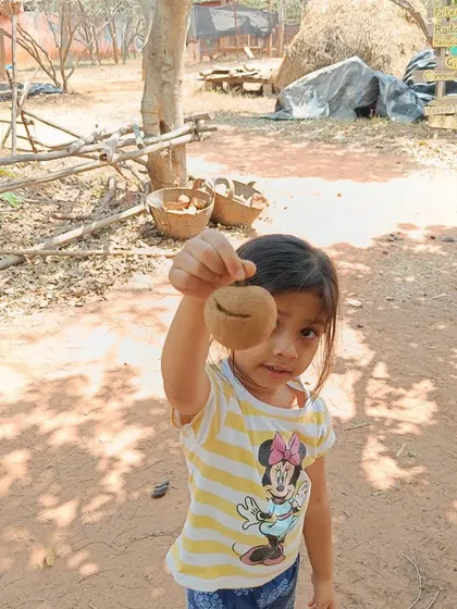 A child proudly shows off a freshly plucked chickoo. The experience of harvesting fruit directly from the tree is a powerful lesson in where food comes from.
